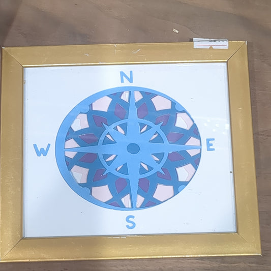 Roughly 5 x 6” gold shadow box with paper cut compass