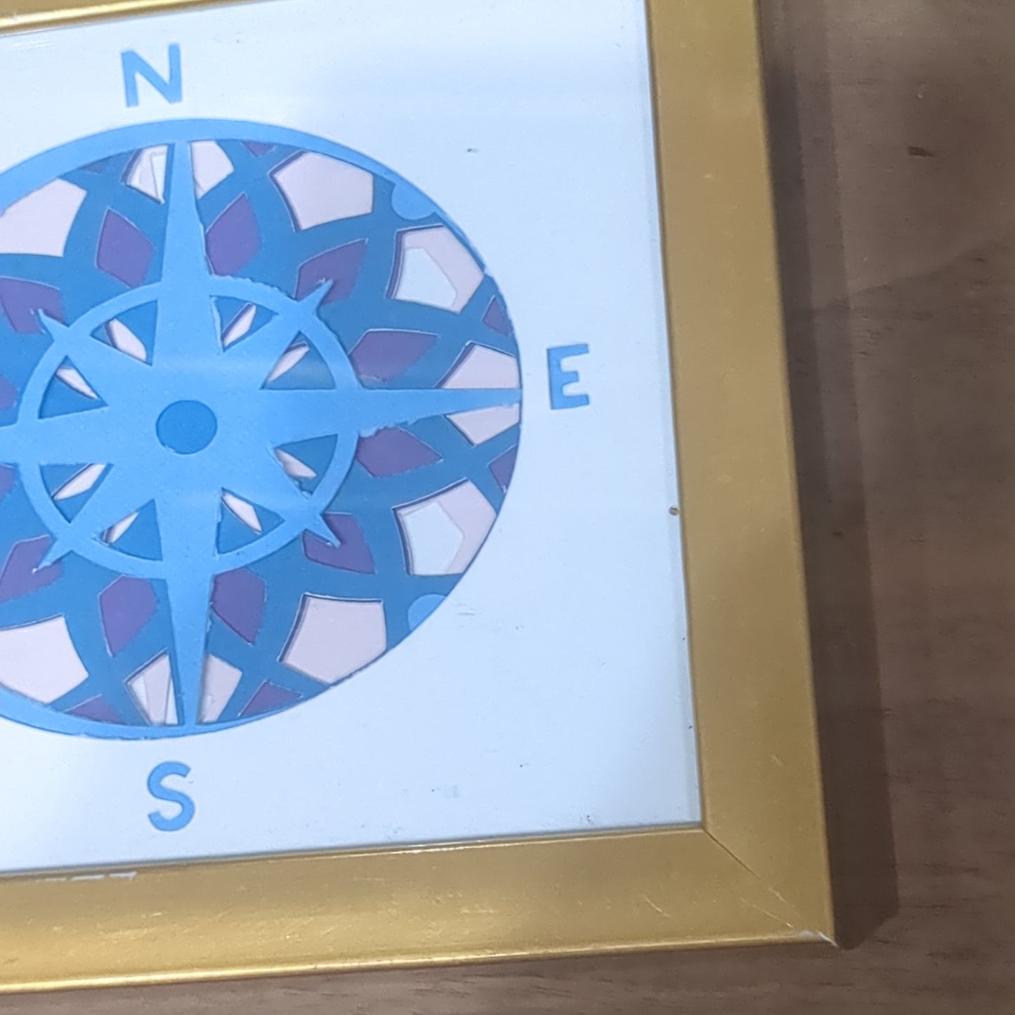 Roughly 5 x 6” gold shadow box with paper cut compass