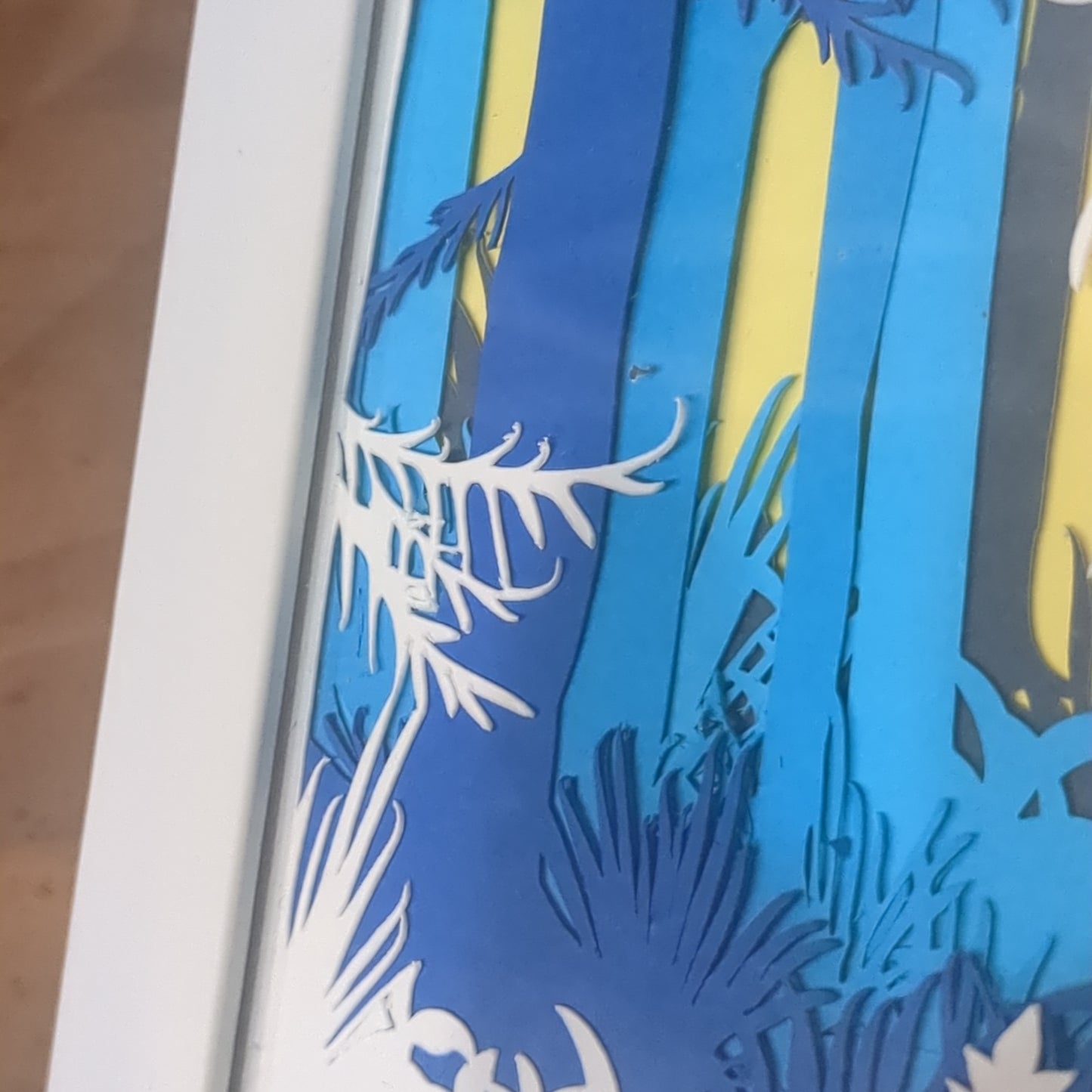 Roughly 5 x 6” white shadow box with paper cut unicorn in Forest serene