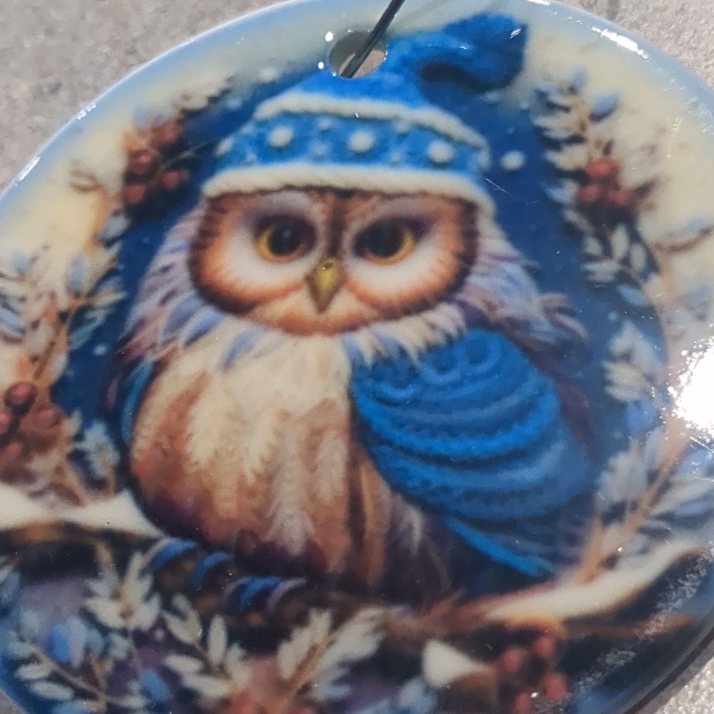 Ceramic ornament with an owl in a dark blue hat and blue scarf, it appears 3D but it is not