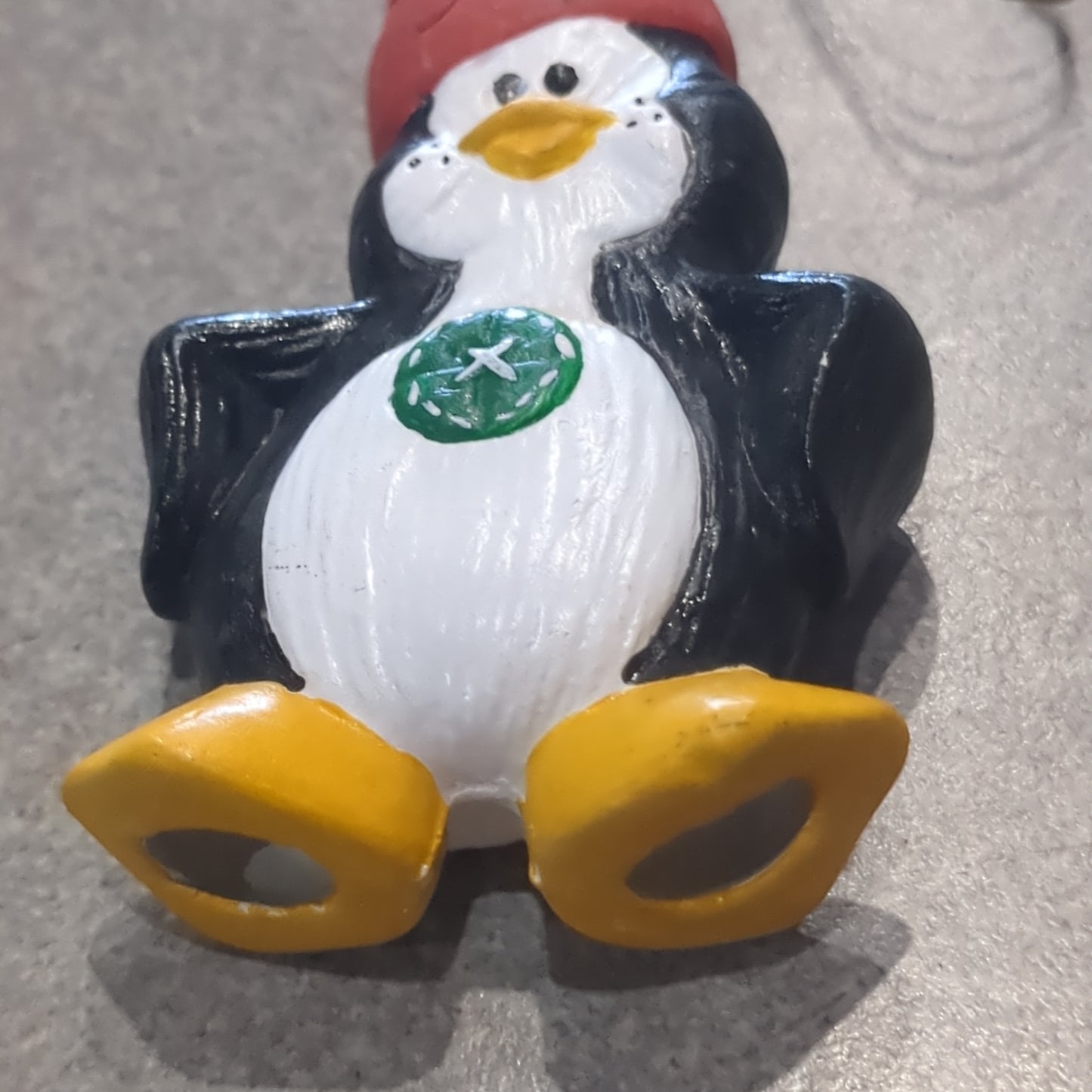 Ceramic penguin ornament with a pot on his head and a button on his belly