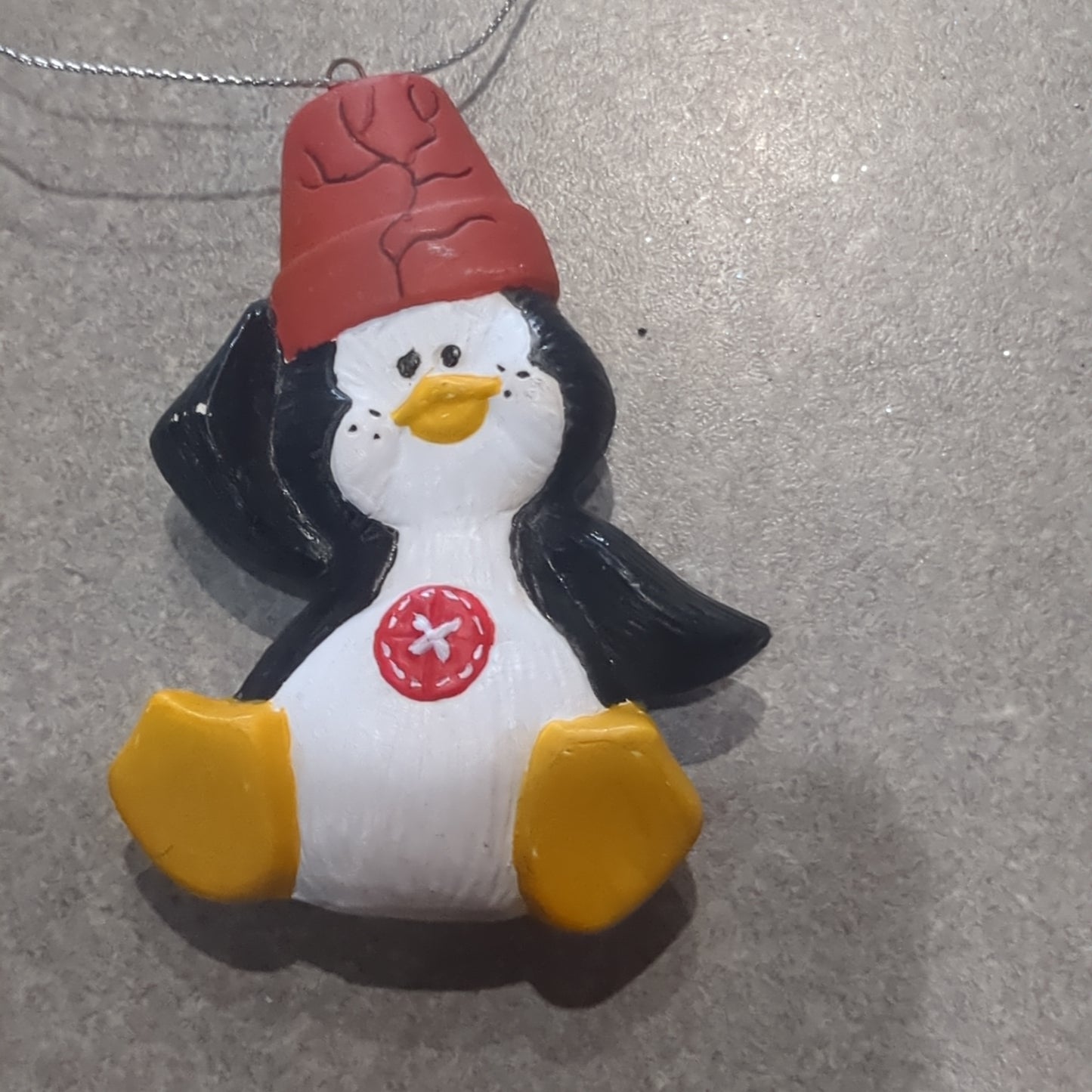 Ceramic penguin ornament with a pot on his head and a button on his belly
