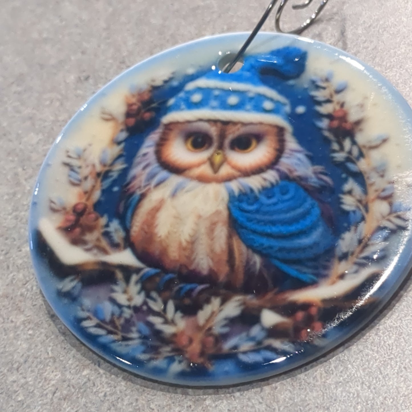 Ceramic ornament with an owl in a dark blue hat and blue scarf, it appears 3D but it is not
