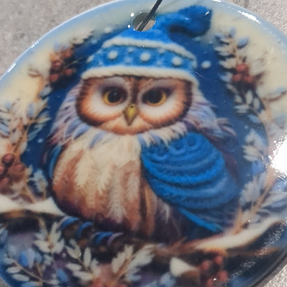 Ceramic ornament with an owl in a dark blue hat and blue scarf, it appears 3D but it is not