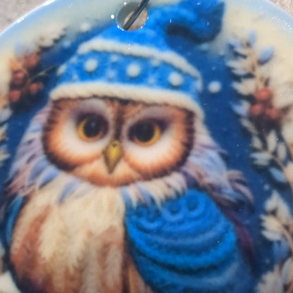 Ceramic ornament with an owl in a dark blue hat and blue scarf, it appears 3D but it is not