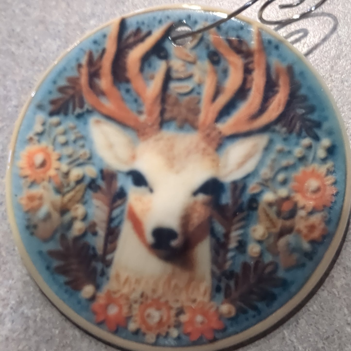 Ceramic ornament with a deer head surrounded by flowers and leaves, it appears 3D but it is not