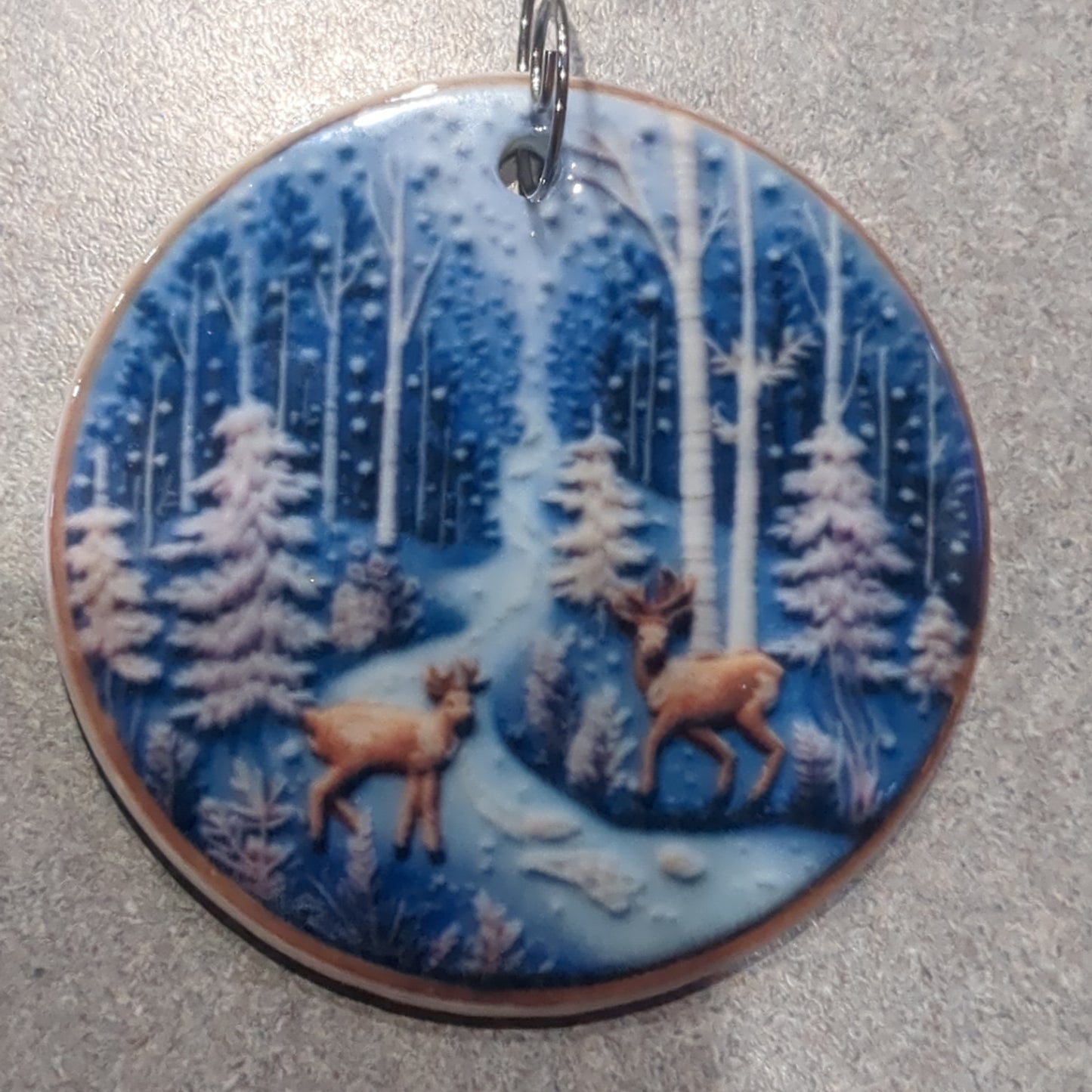 Ceramic ornament with a pair of deer by a river in the forest, it appears 3D but it is not